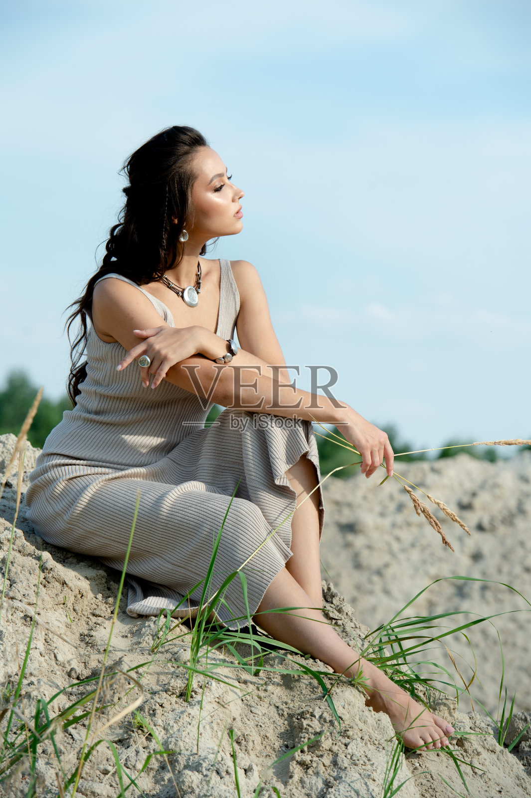 一个悠闲平静的女人的侧影坐在海滩上看日落照片摄影图片