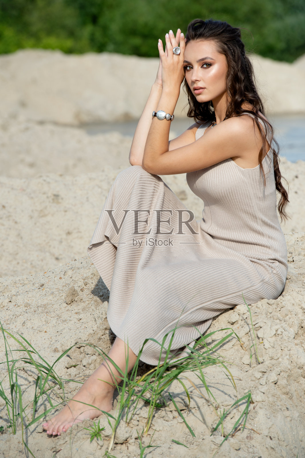 年轻女子戴着时髦的银饰坐在沙滩上照片摄影图片