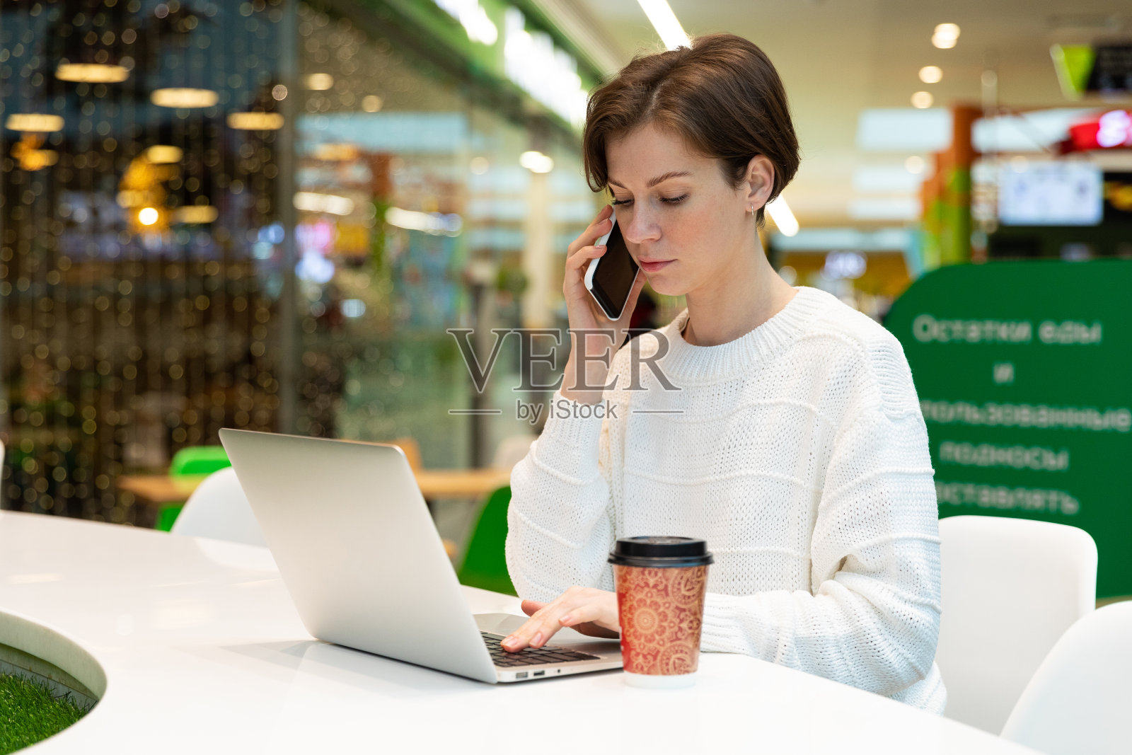 学生在购物中心的咖啡馆里用笔记本电脑工作，自由职业和远程工作的概念照片摄影图片
