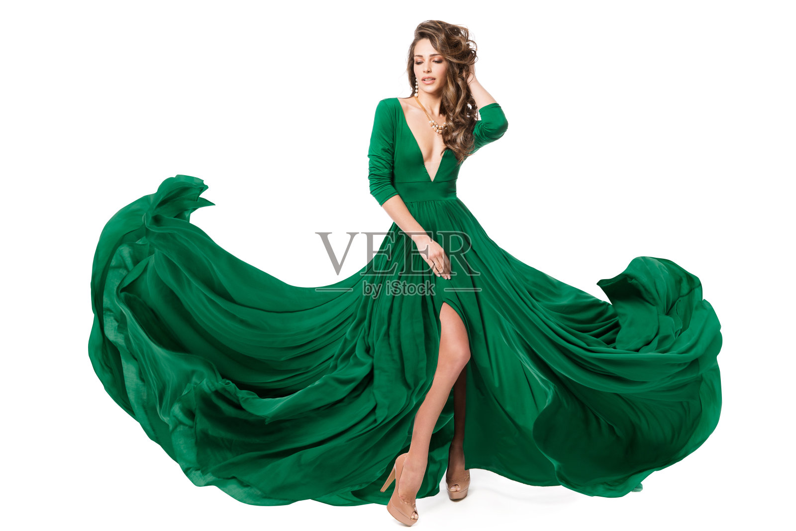 女人绿色时装。模特在风中飘扬的长晚礼服狭缝长袍。时尚美女女孩在孤立的白色背景上跳舞照片摄影图片