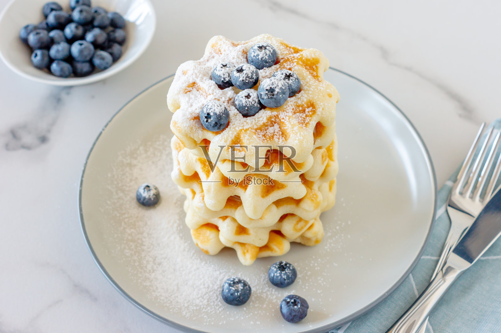 配蓝莓的比利时华夫饼放在浅色的餐桌上，配牛奶。健康的早餐。照片摄影图片