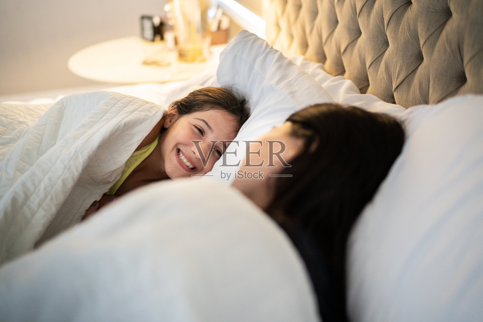 快乐的女孩躺在床上陪妈妈在家照片摄影图片