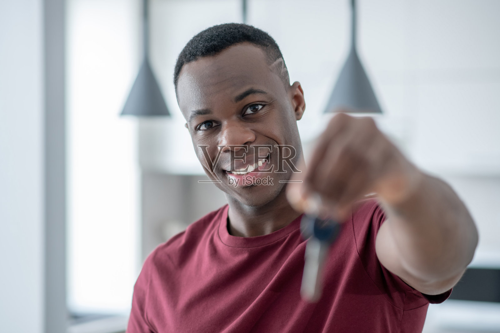 微笑的非裔美国人拿着钥匙，伸出他的手照片摄影图片