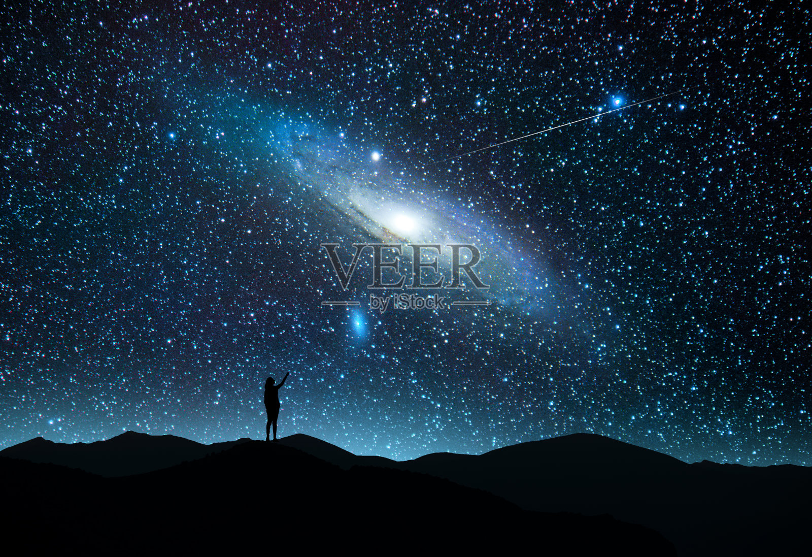 女孩的剪影站在山上，看着仙女座星系和彗星的明亮星空。美丽迷人的夜景。照片摄影图片