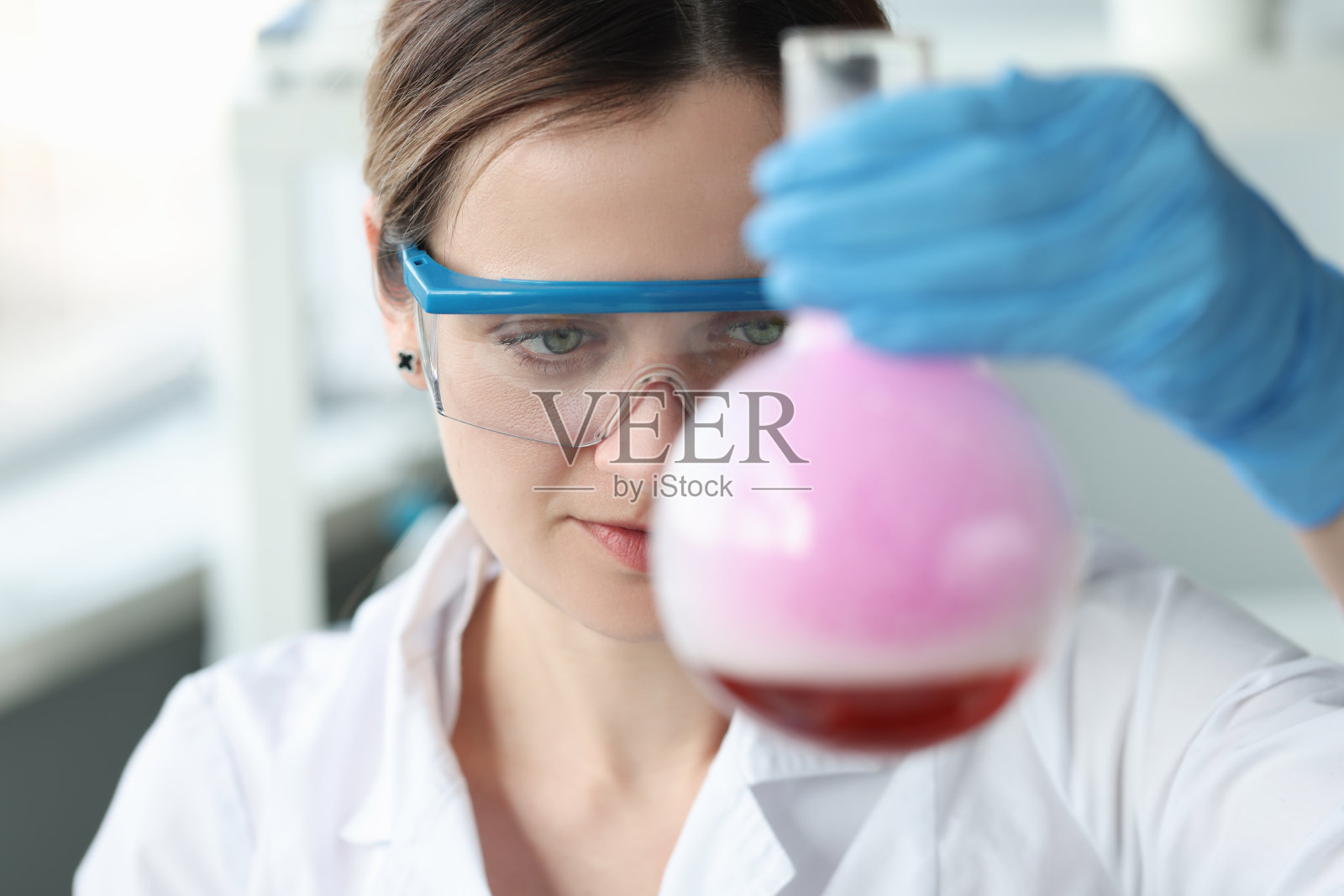 女眼镜研究员正在烧瓶中进行化学实验照片摄影图片