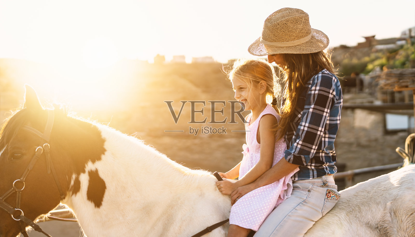幸福的家庭母亲和女儿有乐趣骑马在牧场照片摄影图片