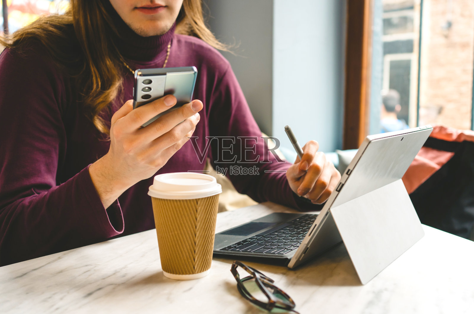 年轻的自由职业者坐在咖啡厅里，用iPad和键盘照片摄影图片