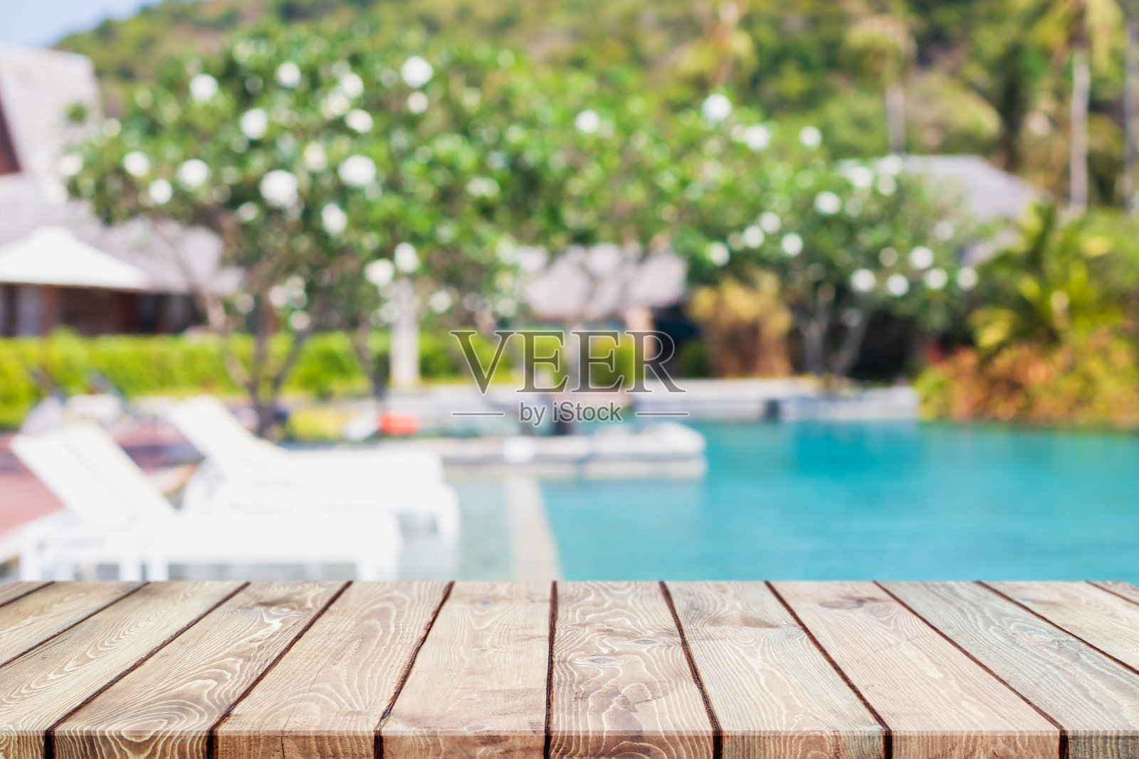 空的木头桌面和模糊的游泳池在夏季的热带度假胜地横幅背景-可以用来展示或蒙太奇您的产品。照片摄影图片