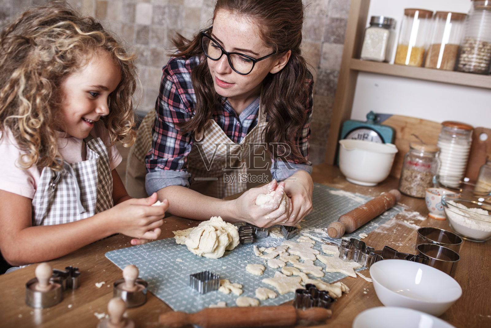母亲和女儿在厨房里玩耍和准备面团。家庭的概念。照片摄影图片