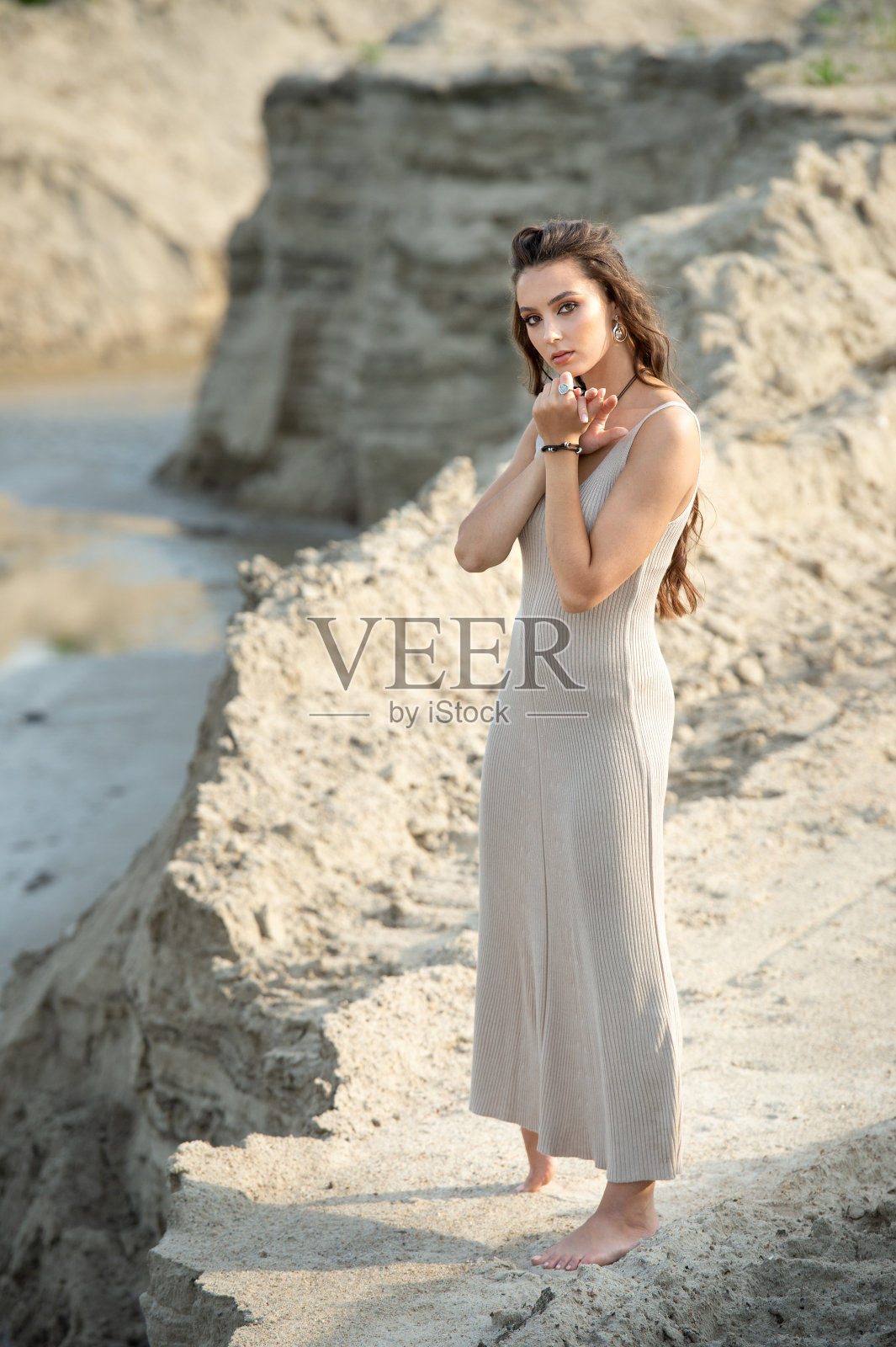 年轻的女人在一个时髦的夏季亚麻布裙子摆姿势在海边的海滩上照片摄影图片