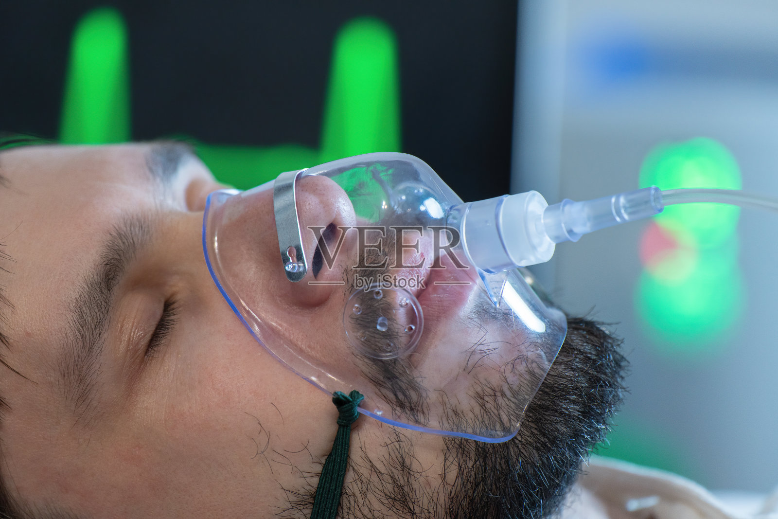 在covid-19大流行期间，一名年轻男子在医院戴着氧气面罩呼吸。照片摄影图片