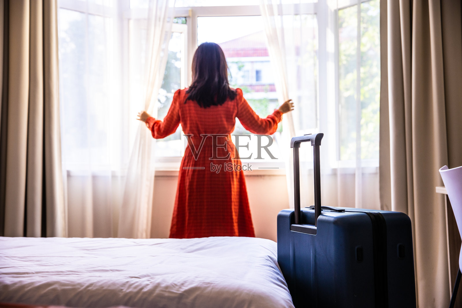 一个年轻女子正在拉开酒店房间的窗帘照片摄影图片