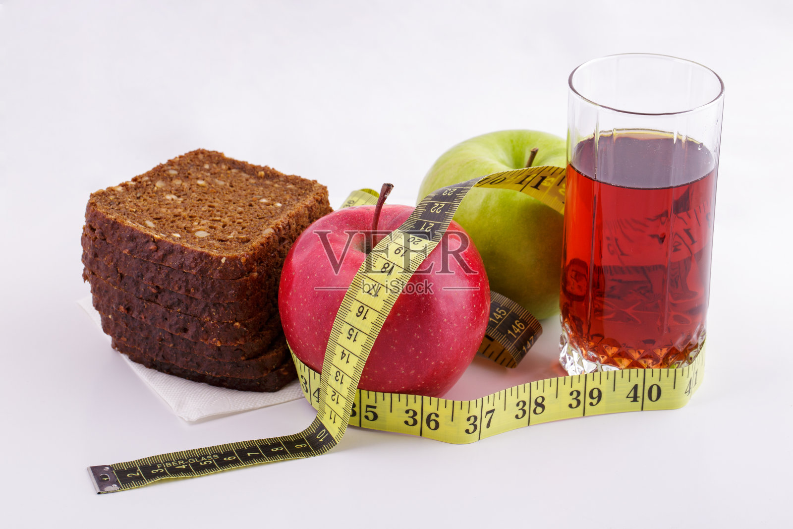黑麦面包，绿苹果和红苹果，果汁装在一个白色盘子里，用黄色的卷尺。饮食与健康食品理念照片摄影图片