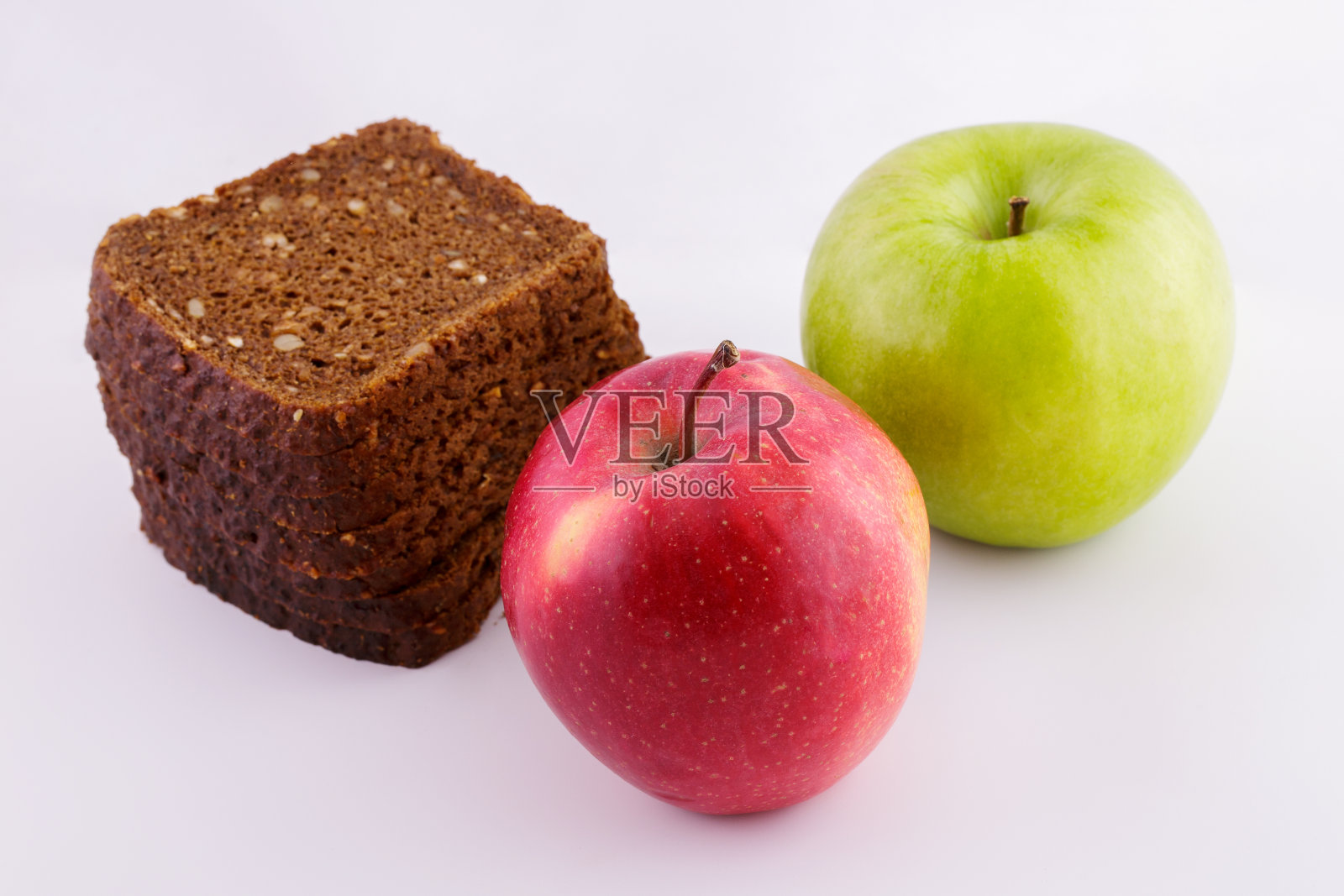 切成薄片的黑麦面包在白色的背景和红绿的苹果照片摄影图片