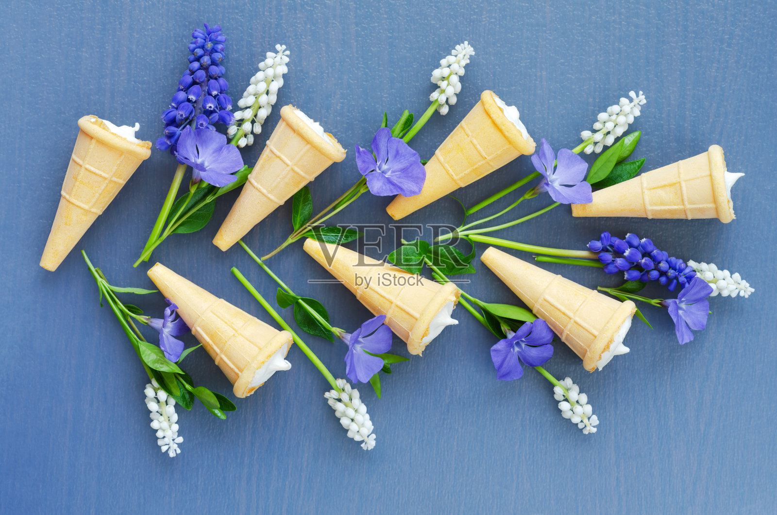 美味的甜点华夫蛋筒在蓝色的背景和春天的花。俯视图照片摄影图片