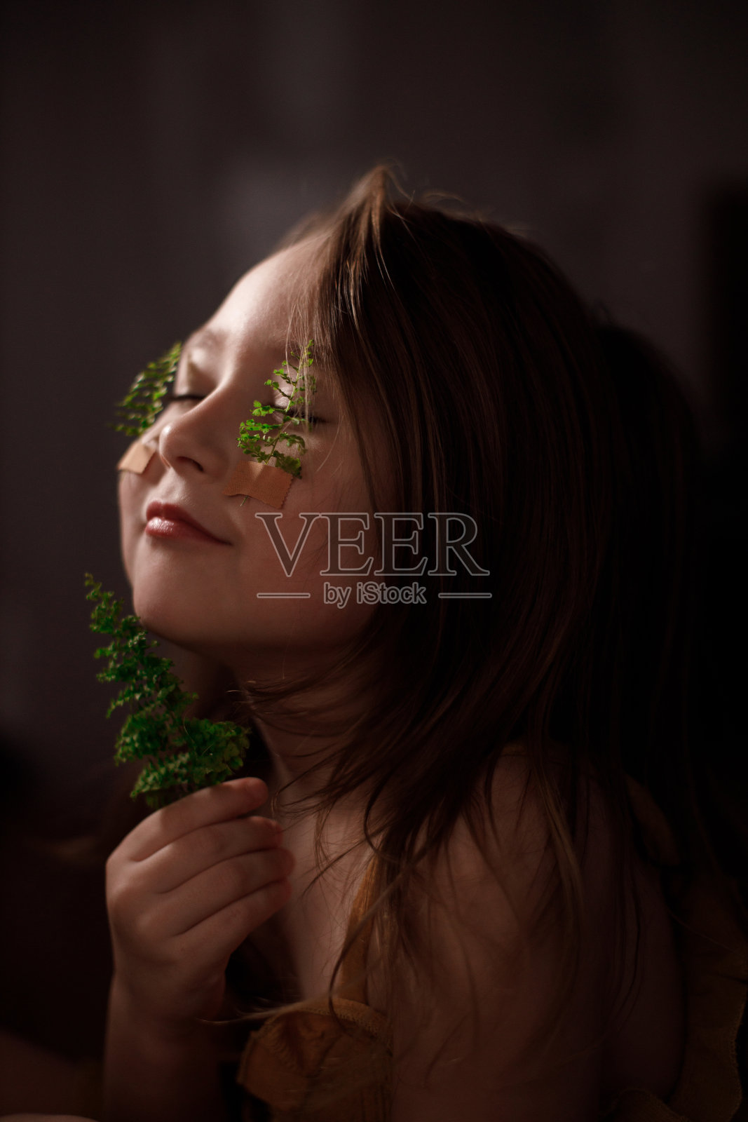 生态学概念，孩子的肖像与蕨类植物的小枝贴在她的脸颊上，拿着小枝照片摄影图片