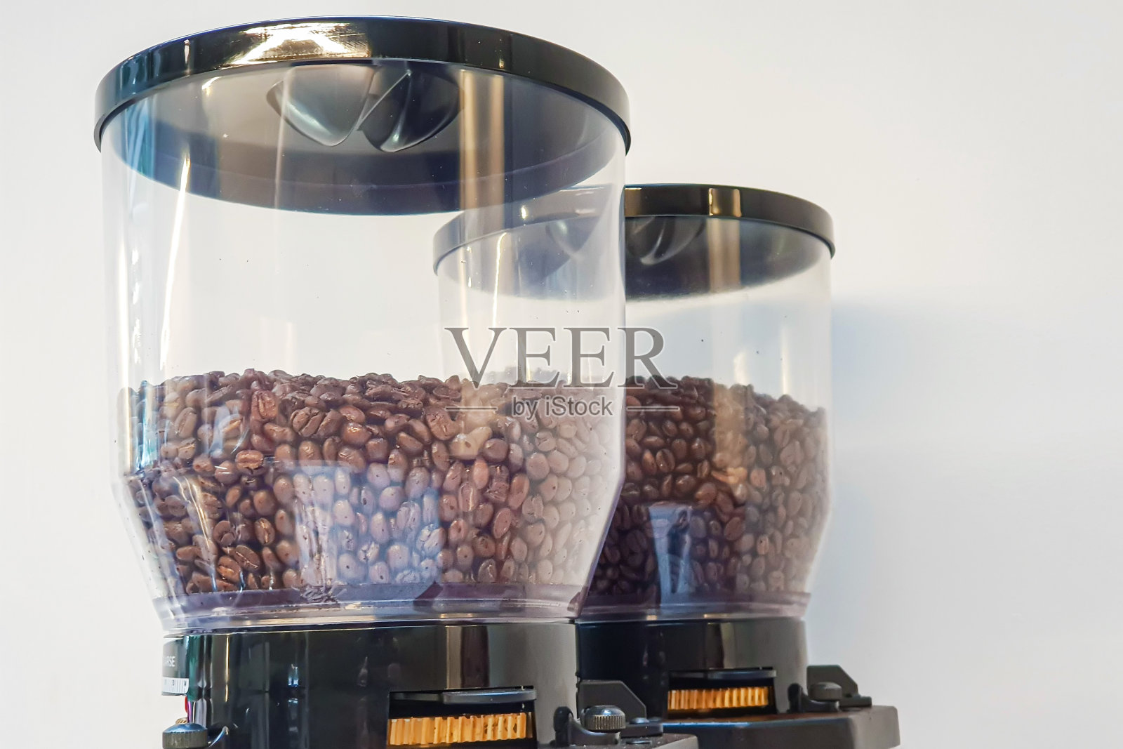 白色背景的咖啡机上的透明罐子里的咖啡豆照片摄影图片
