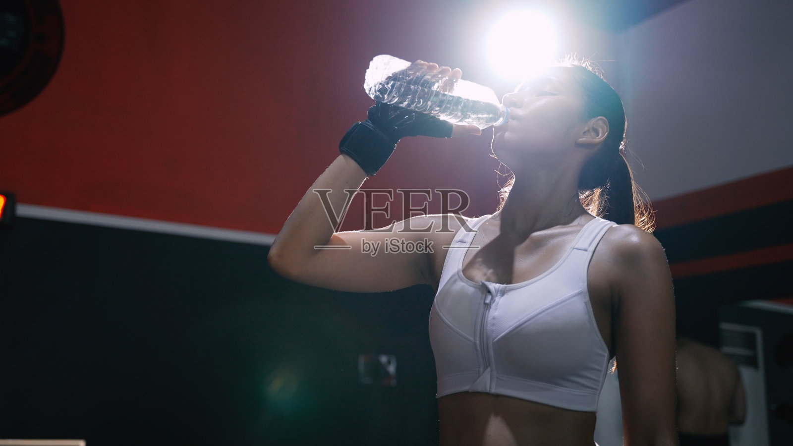 运动员亚洲妇女饮用纯净水后锻炼或训练建立肌肉和燃烧脂肪心脏，刷新身体健康的生活方式在健身馆。照片摄影图片