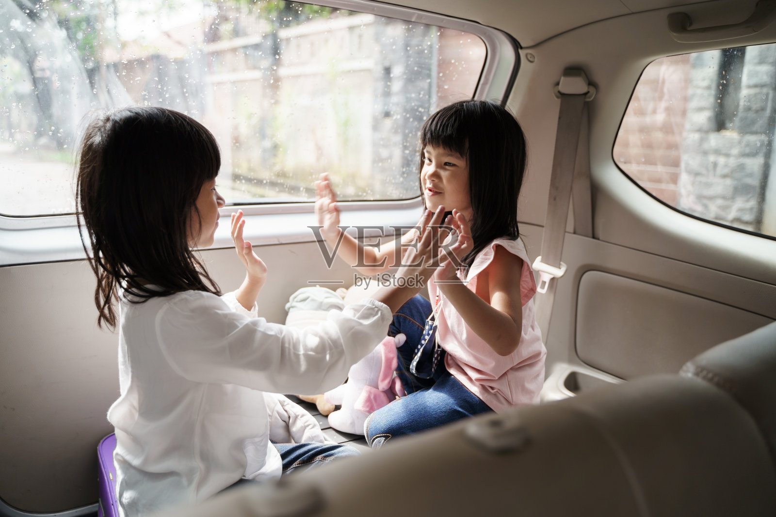 两个快乐的孩子坐在汽车后备箱里一起玩耍照片摄影图片