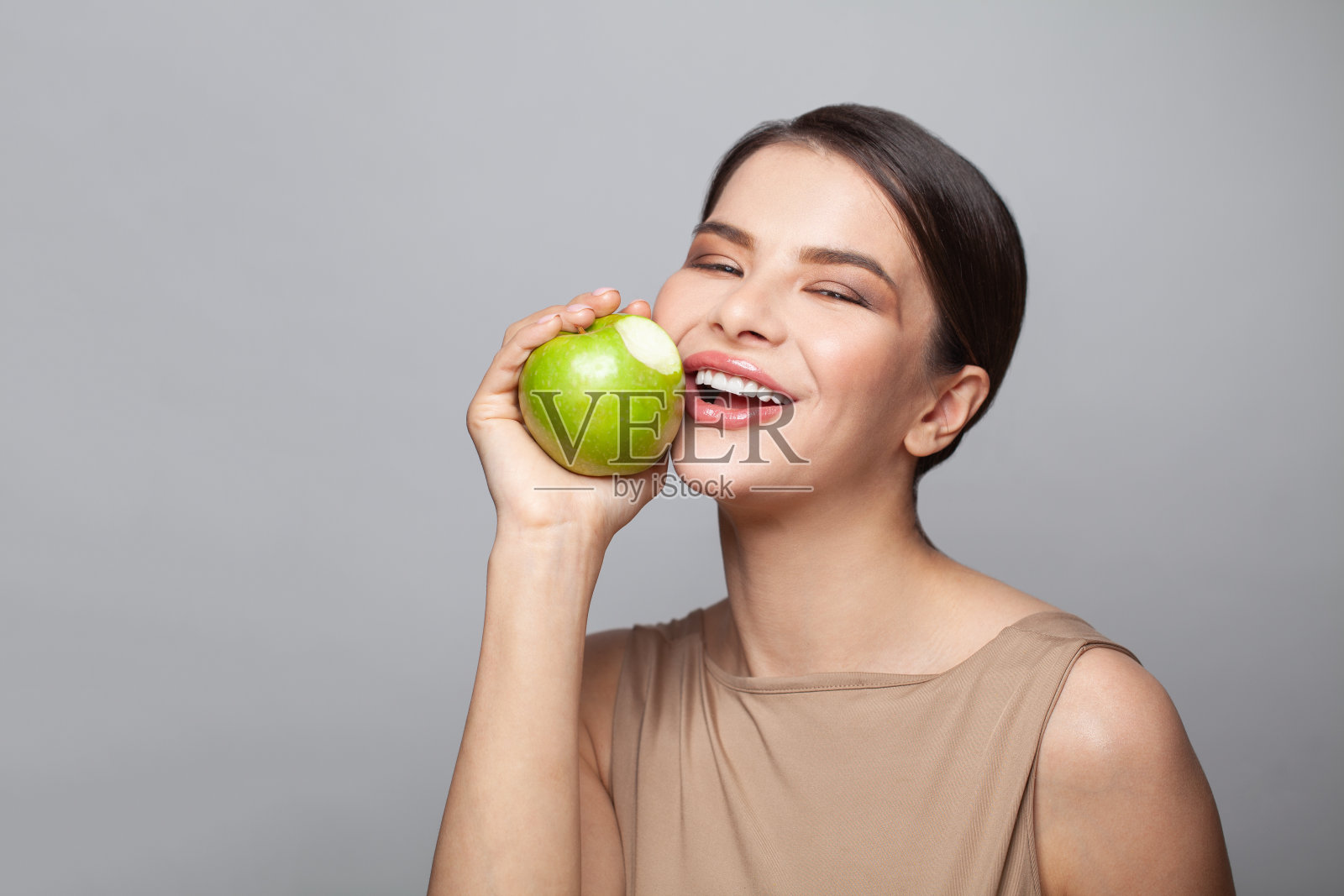 一个年轻女子微笑着吃着苹果的肖像照片摄影图片