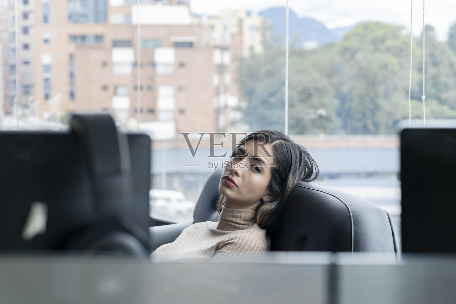 一位拉丁妇女坐在她办公室的沙发上，脸上带着悲伤的表情照片摄影图片