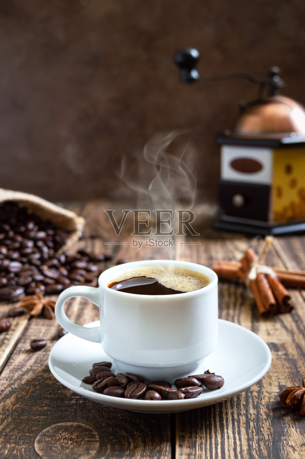 热气腾腾的咖啡放在一张旧木桌上，上面放着咖啡豆，还有手工磨咖啡机。俯视图照片摄影图片