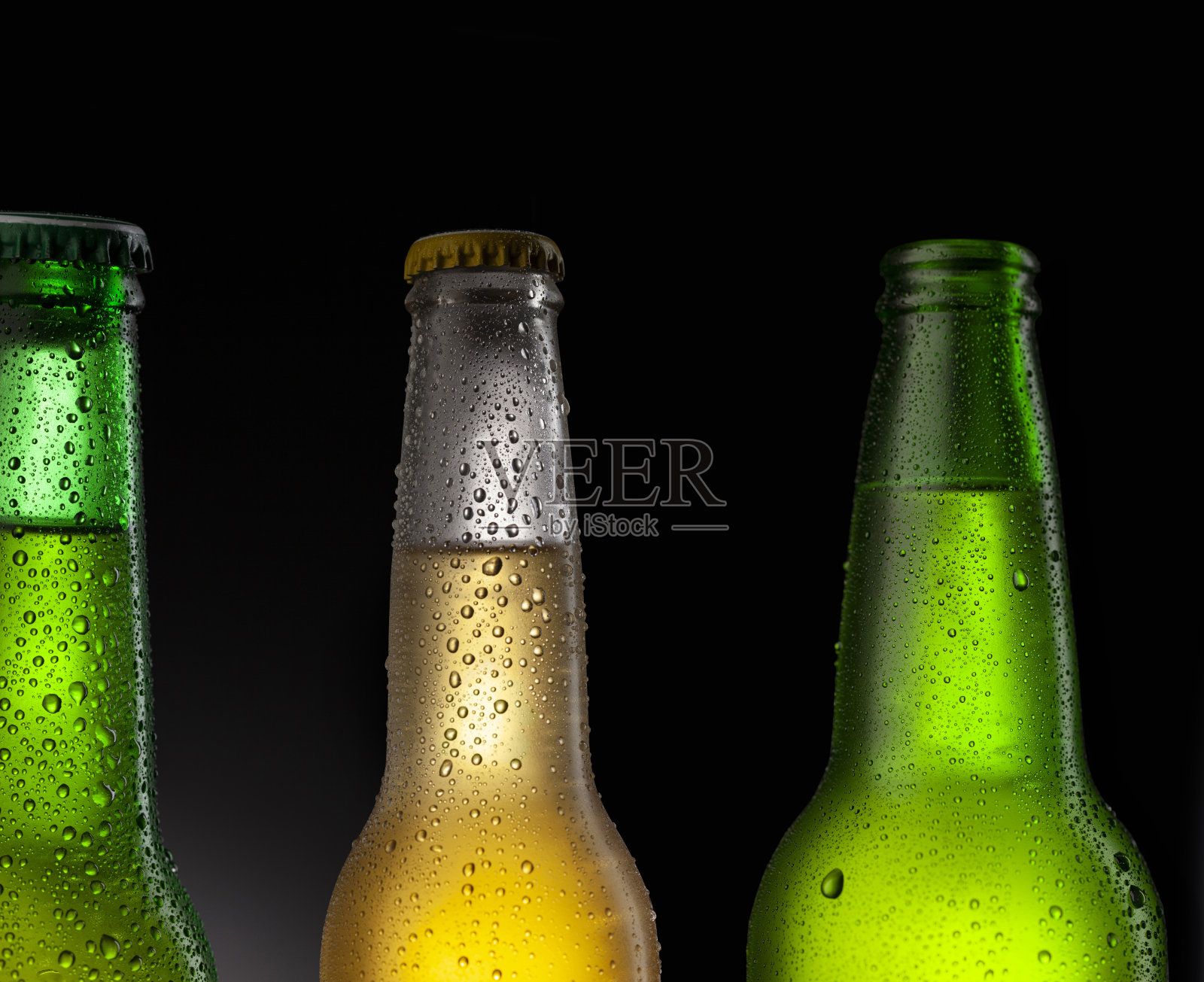冰镇的啤酒瓶上覆盖着冰和水滴。空白饮料饮料产品设计模型。站在黑色的桌子上，黑色的背景。照片摄影图片