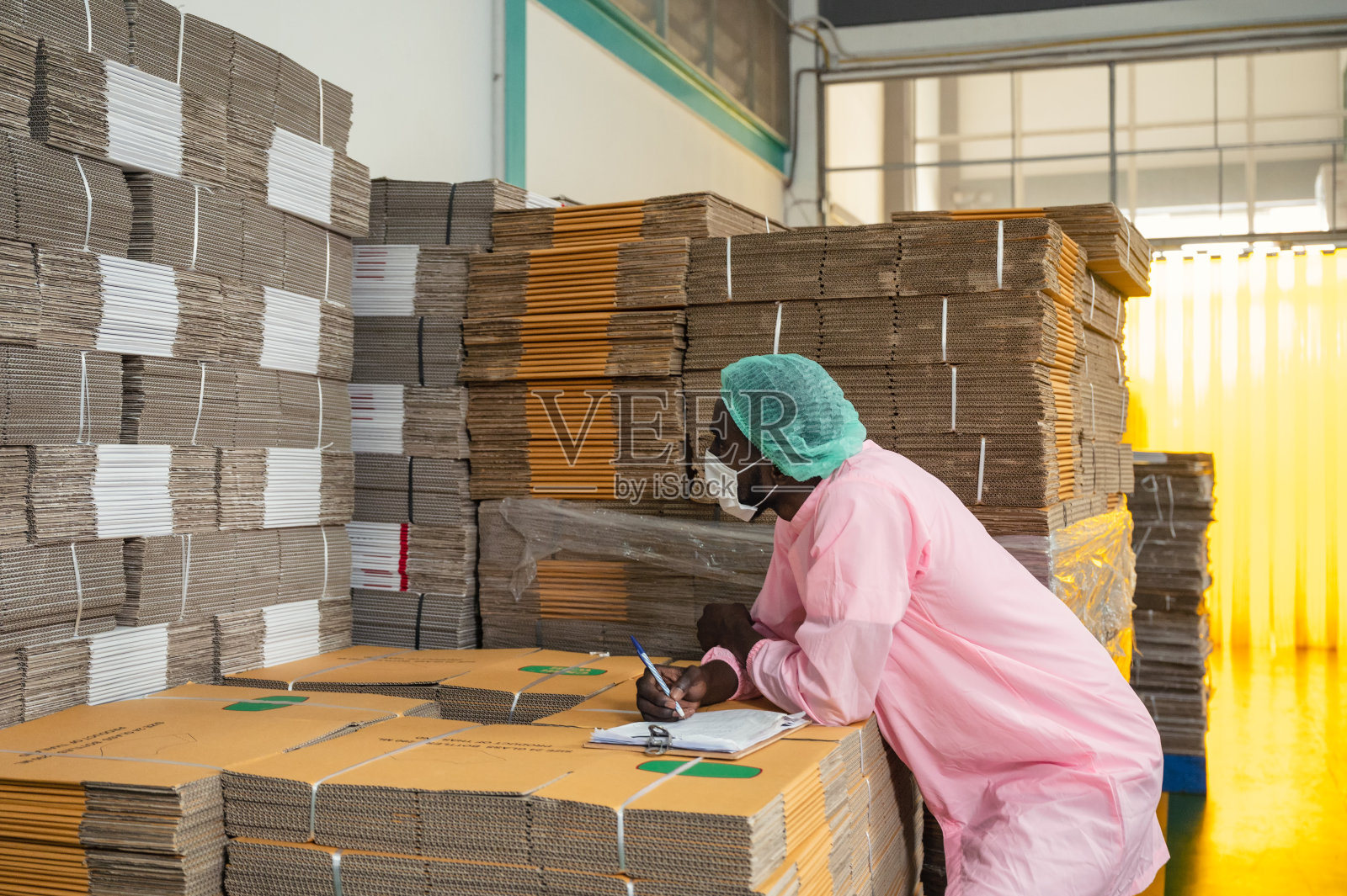 非洲人库存控制经理在无菌衣物检查顺序纸箱包装堆放在仓库照片摄影图片