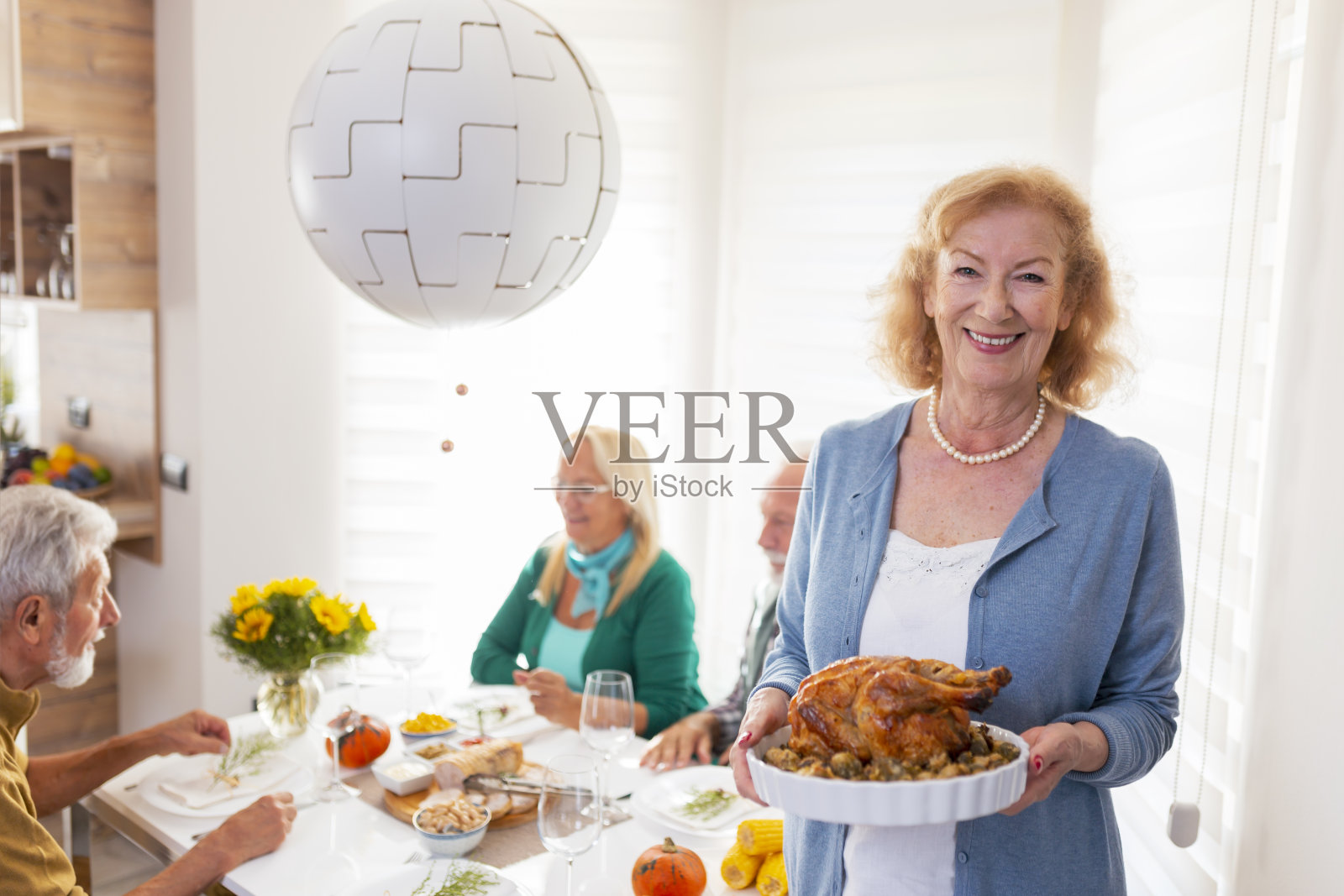 一位年长的女士为朋友们提供感恩节晚餐的烤鸡照片摄影图片