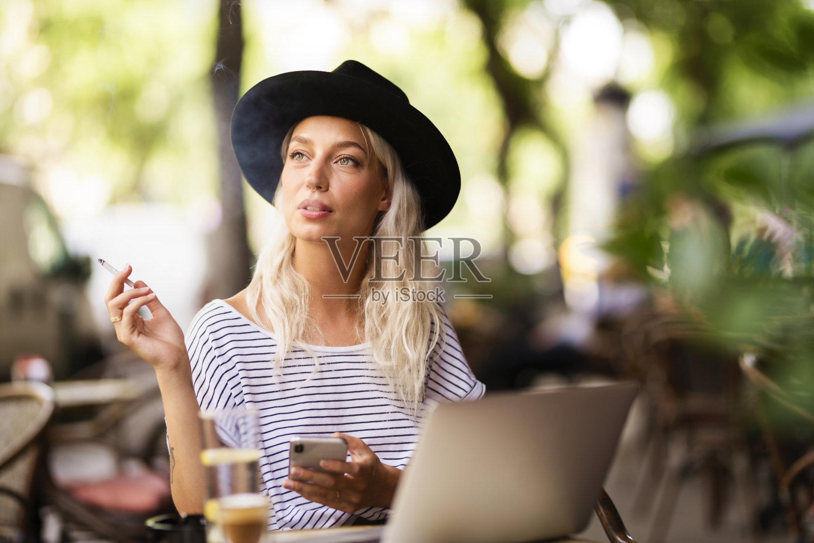 一个快乐的年轻女人坐在露天咖啡馆的露台上抽烟照片摄影图片