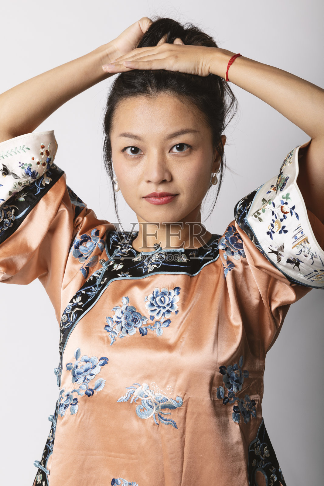 年轻的亚洲女孩穿着传统的中国衬衫收集她的头发。工作室肖像照片摄影图片