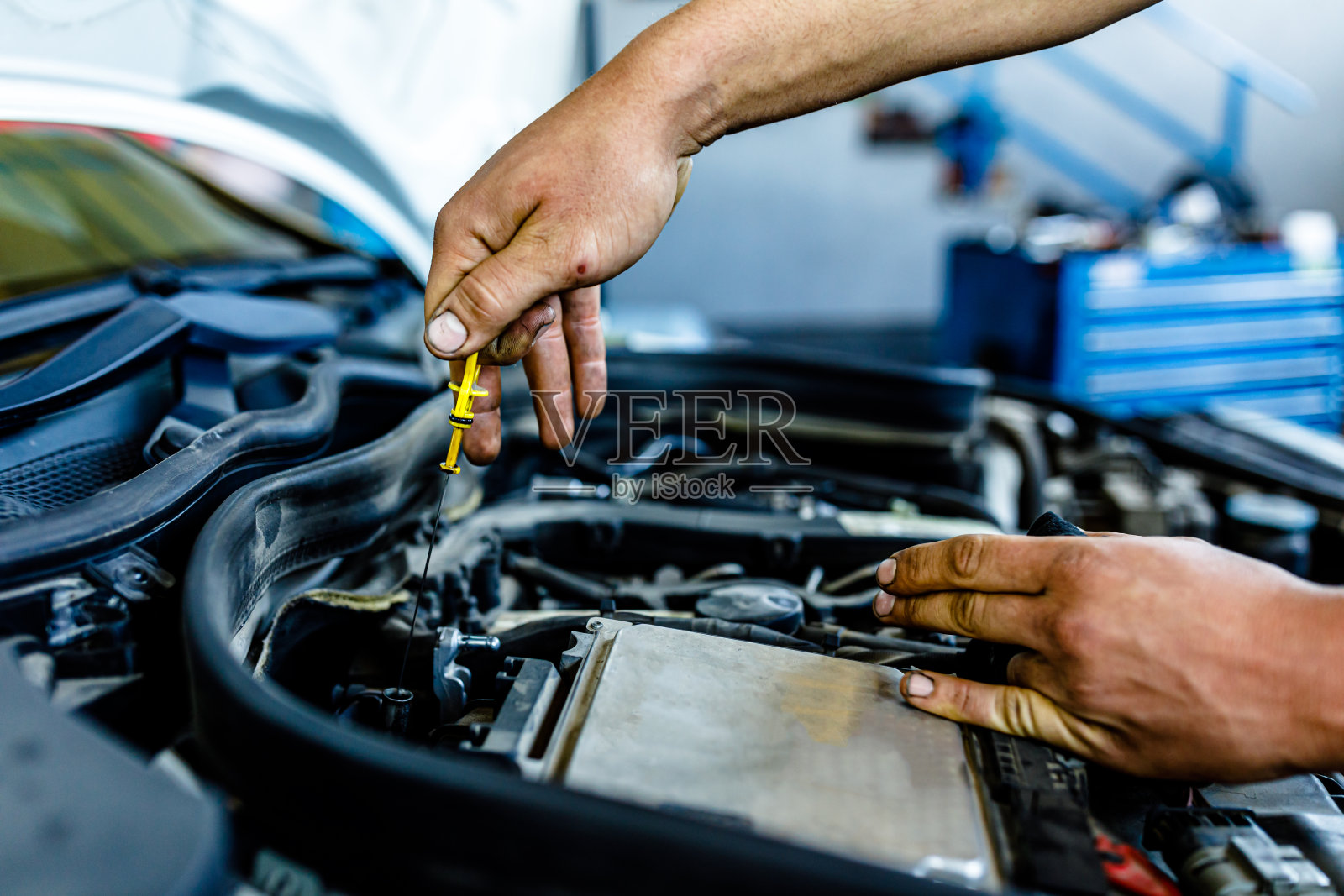 图为一位经验丰富的汽车修理工正在给汽车的发动机换油。照片摄影图片
