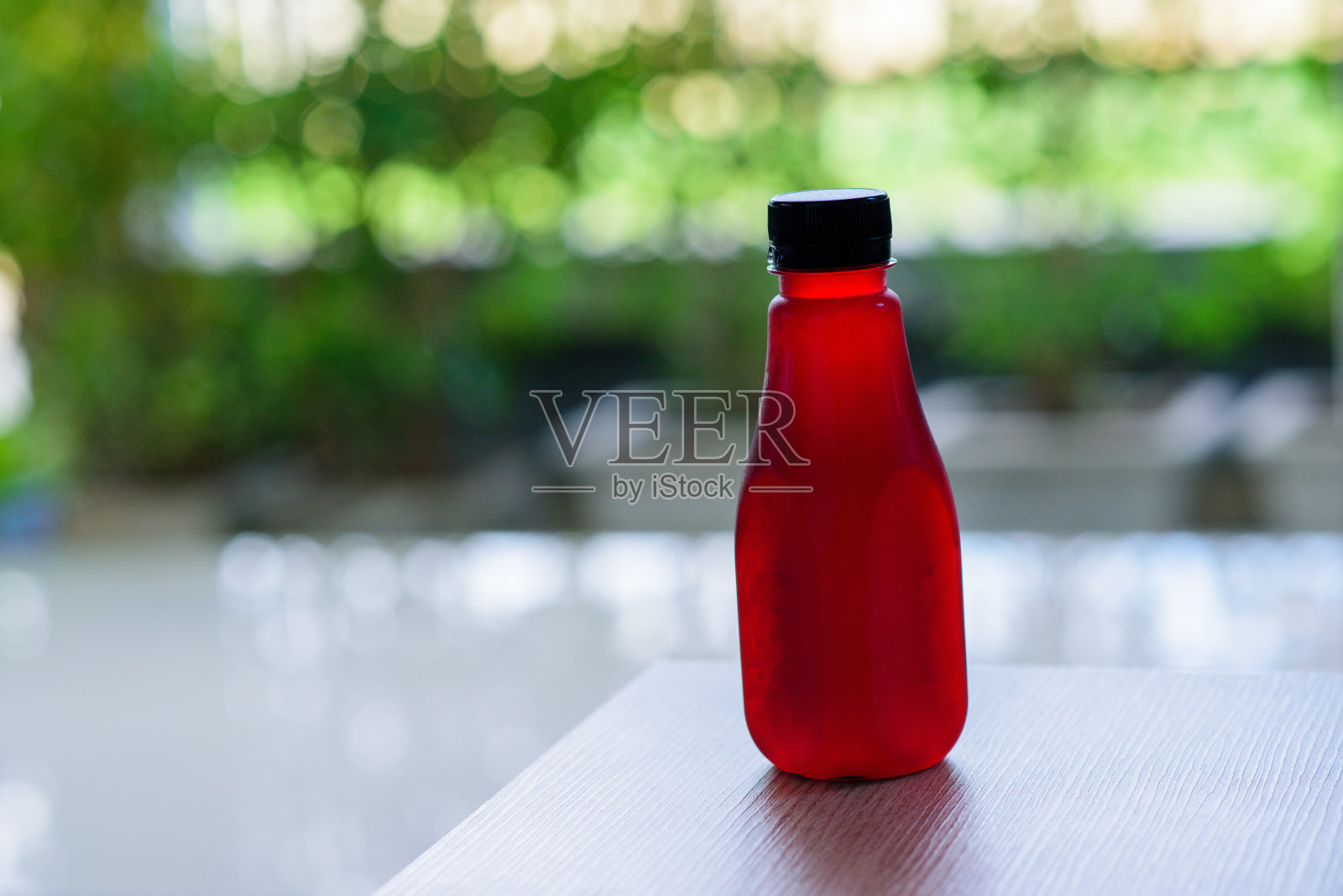 玫瑰汁在一个塑料瓶与自然的绿色背景照片摄影图片