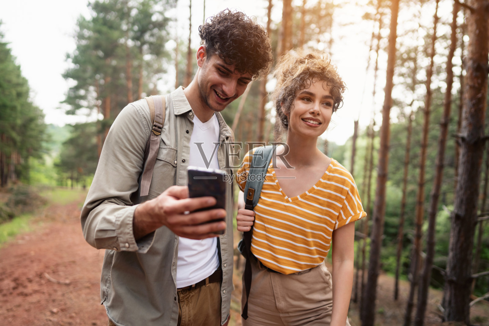 快乐的年轻徒步旅行者使用智能手机上的GPS地图在树林中导航照片摄影图片