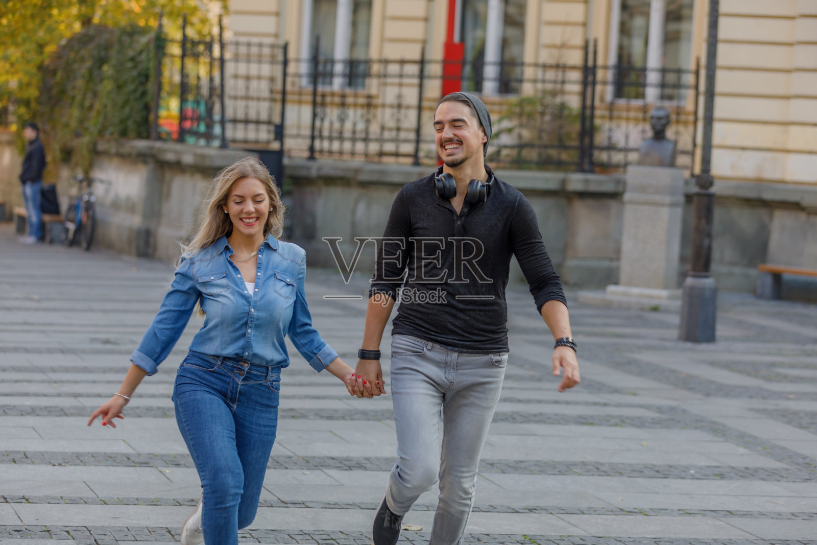 一对快乐的年轻夫妇的肖像，他们走在城市的街道上，有一个愉快的谈话。照片摄影图片