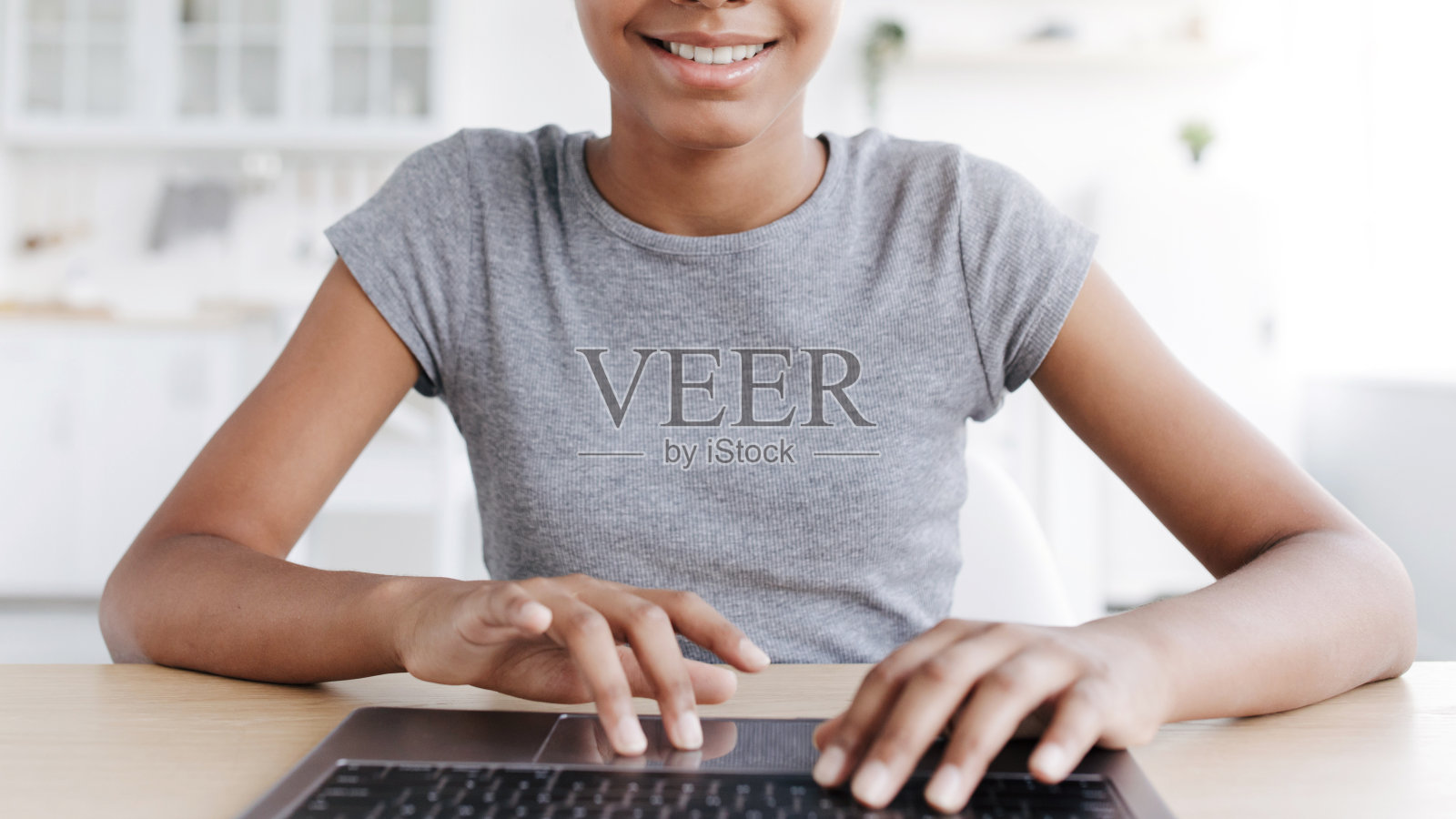 微笑的十几岁非洲裔美国女孩在键盘上打字，在家里的笔记本电脑上学习照片摄影图片