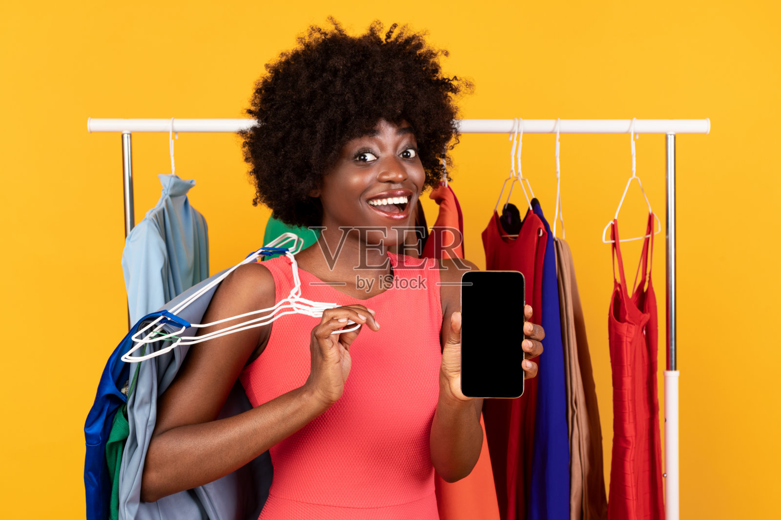 兴奋的非洲裔美国人购物狂女人显示手机屏幕，黄色背景照片摄影图片