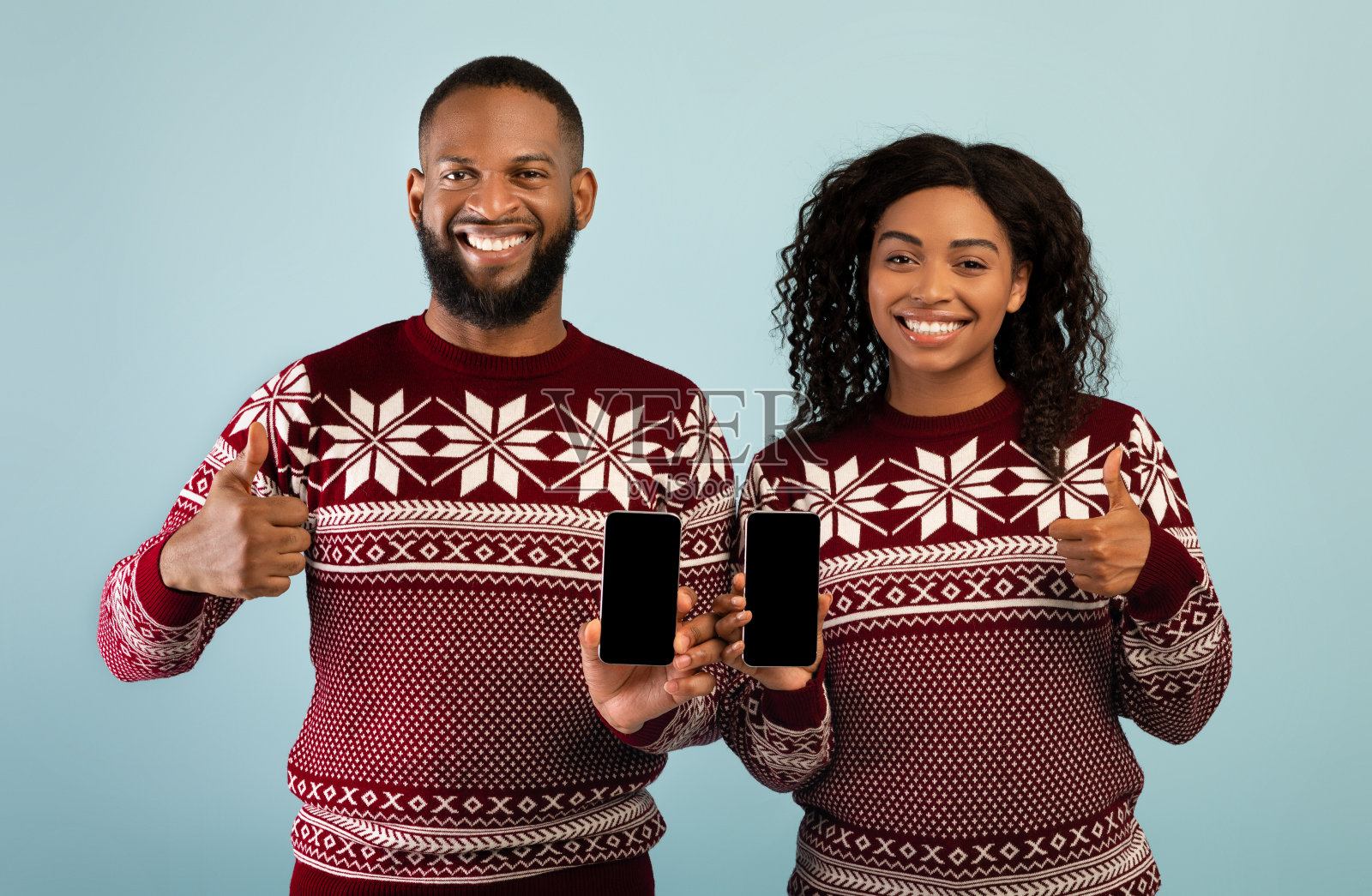 圣诞网上购物。快乐的非裔美国人配偶展示着空屏幕的智能手机，竖起大拇指照片摄影图片