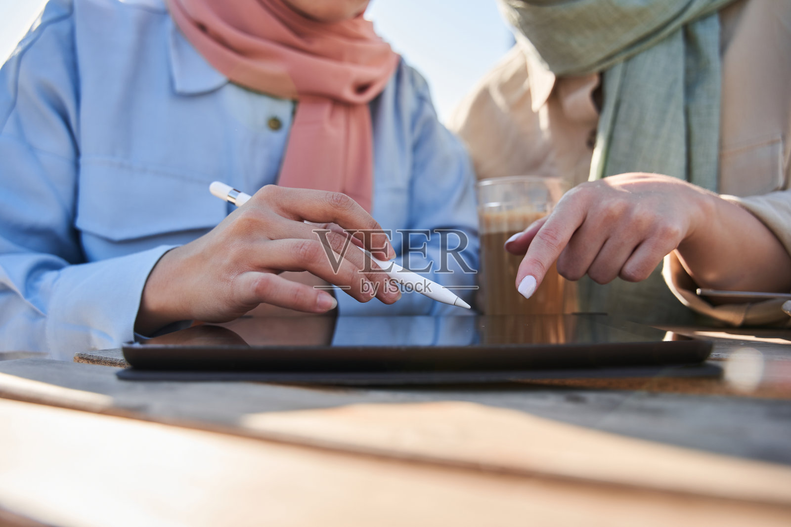 两个戴着围巾的女人参与了平板电脑的工作照片摄影图片