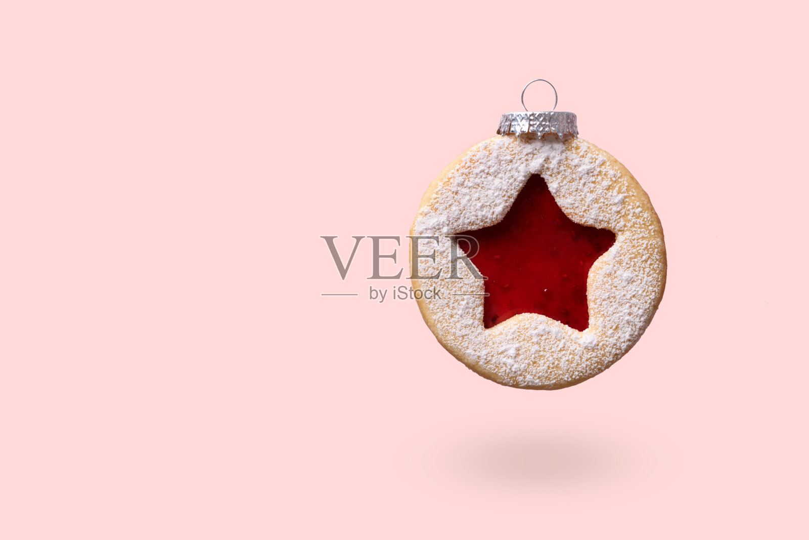由林瑟饼干做成的圣诞装饰物漂浮在粉红色的背景上。最小的圣诞背景照片摄影图片