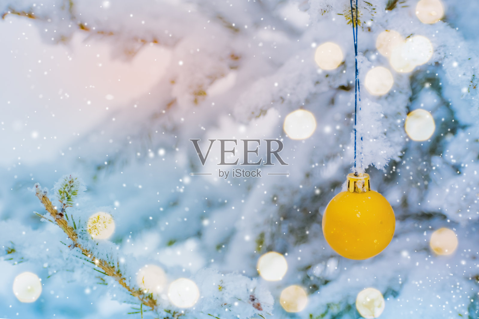 冬天的森林里，圣诞球挂在一棵被雪覆盖的圣诞树的树枝上。贺卡或横幅假日背景与复制空间照片摄影图片