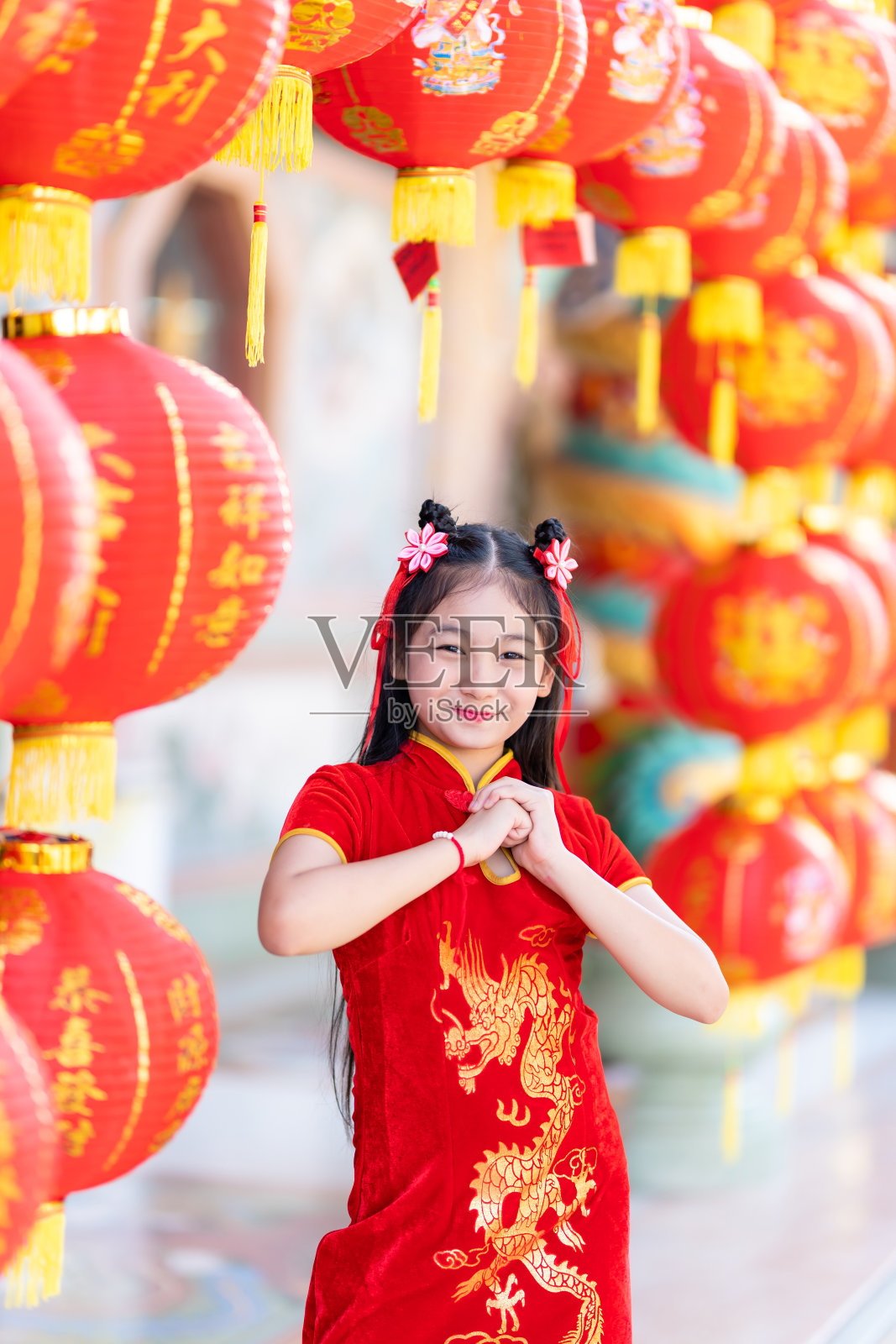 可爱的亚洲小女孩，穿着中国传统旗袍，红色的纸灯笼，上面写着中国的字母祝福，是中国新年吉祥的赞美装饰照片摄影图片
