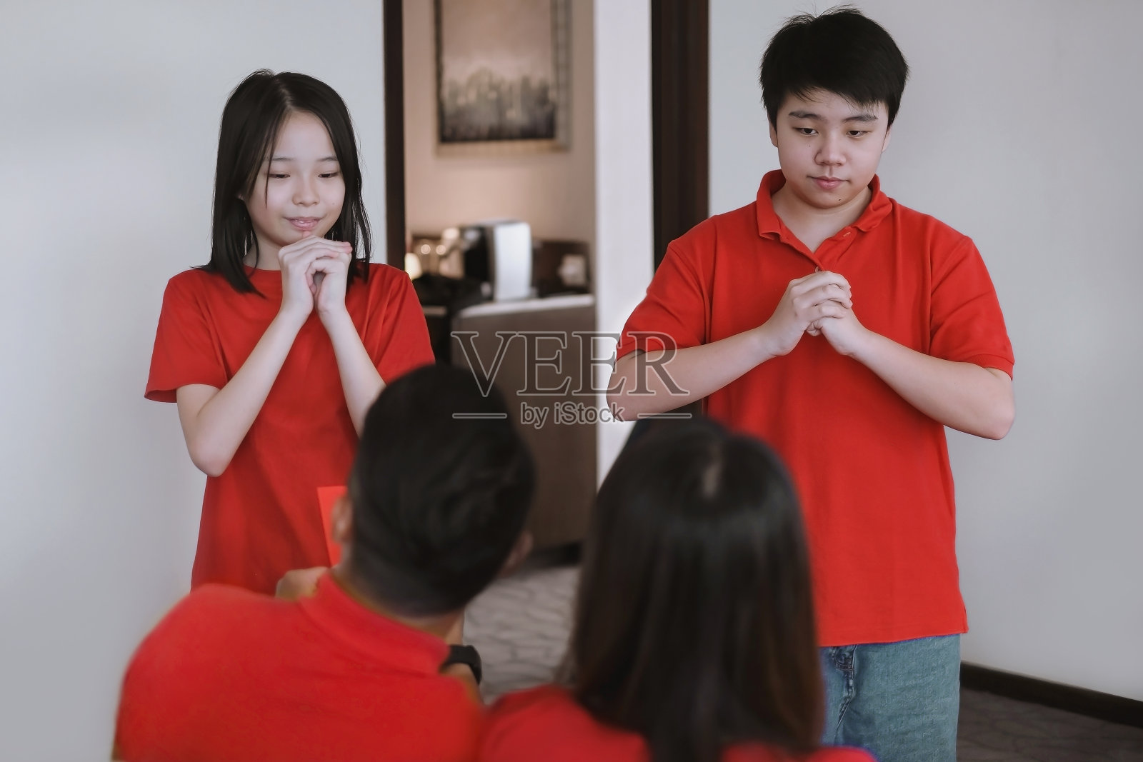 亚洲的兄弟姐妹在中国新年用恭喜的手势问候父母照片摄影图片