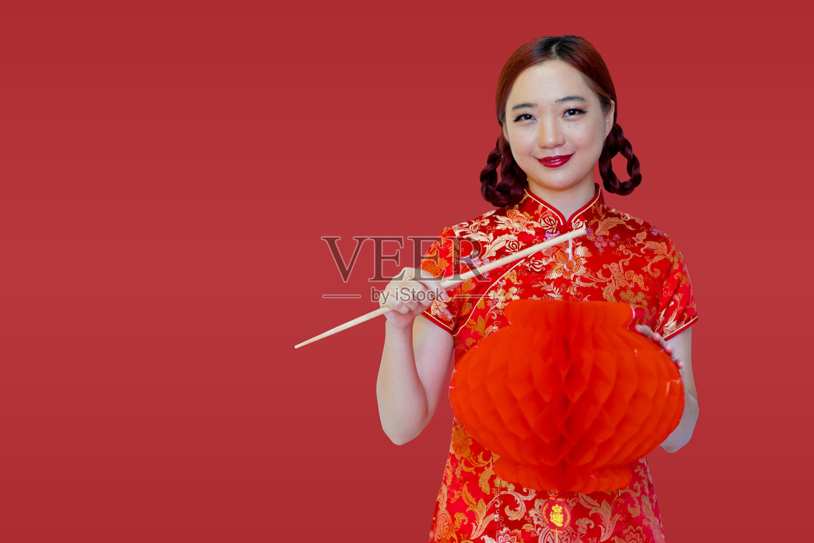 美丽年轻的亚洲妇女在中国传统的旗袍旗袍，拿着一个中国灯笼在红色的背景。中国新年观念照片摄影图片