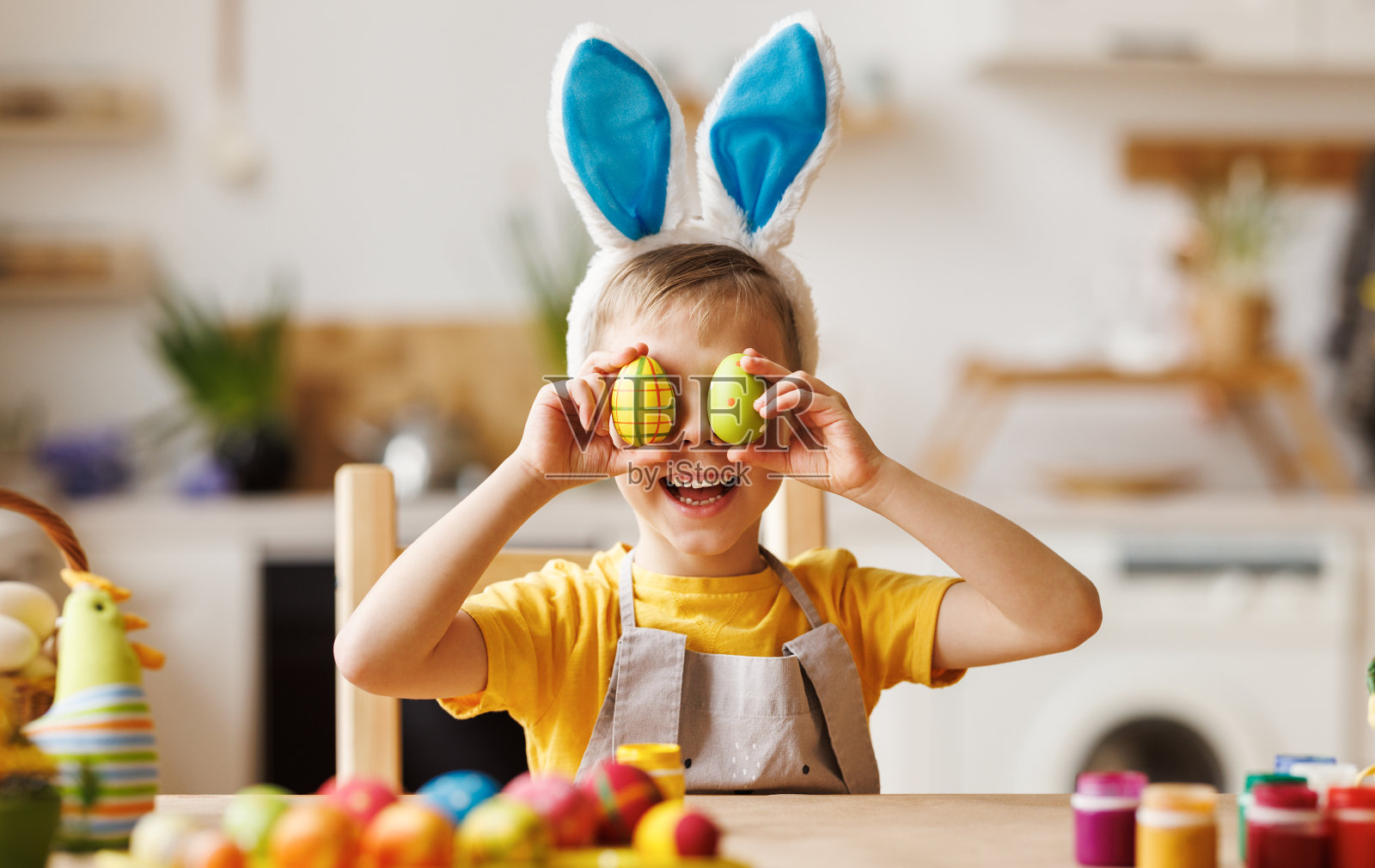 有趣快乐的小男孩，头上戴着毛绒兔子耳朵，眼睛上戴着五彩缤纷的复活节彩蛋照片摄影图片