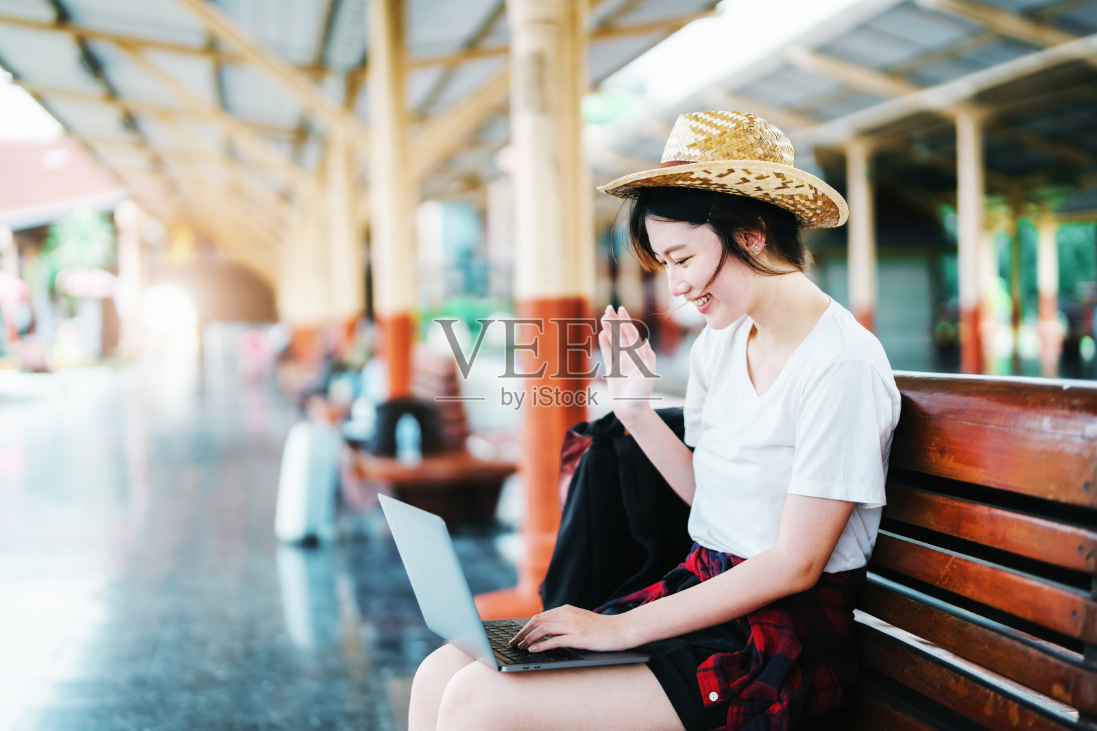 夏天，放松，假期，旅行，肖像美丽的亚洲女孩在火车站使用笔记本电脑，等待他们的旅行时间。照片摄影图片