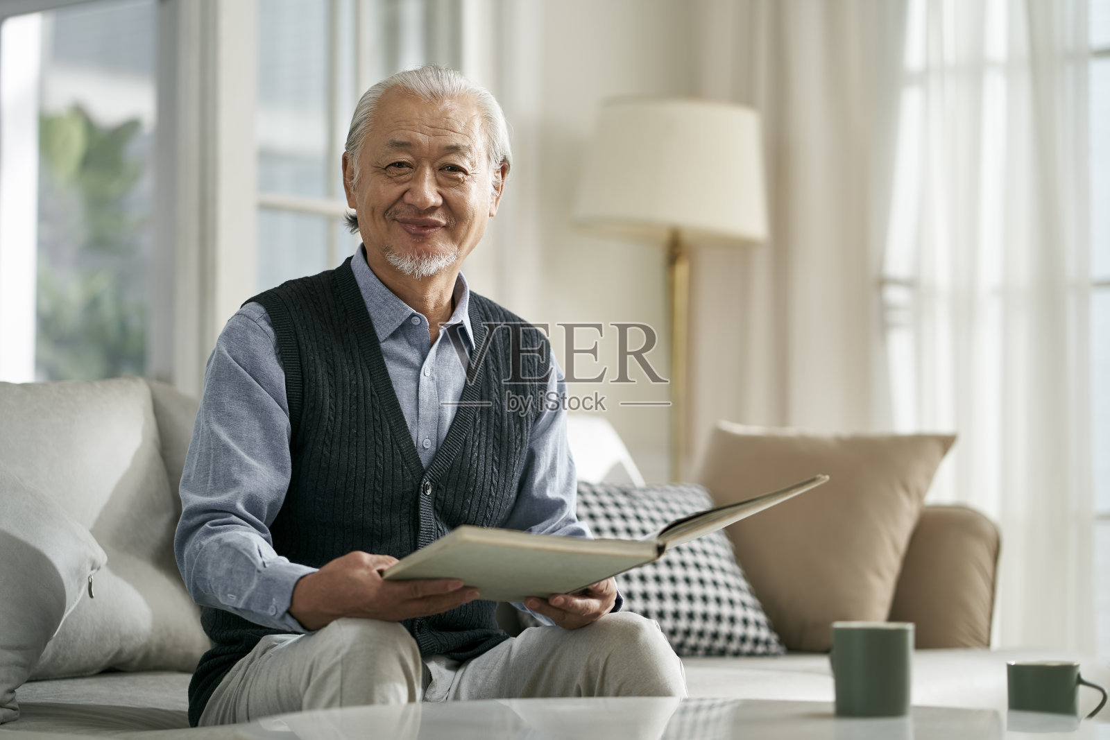 快乐的亚洲老人在家看书照片摄影图片