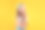 惊讶的小女孩穿着夏天的衣服，背景是黄色。假期的概念素材图片