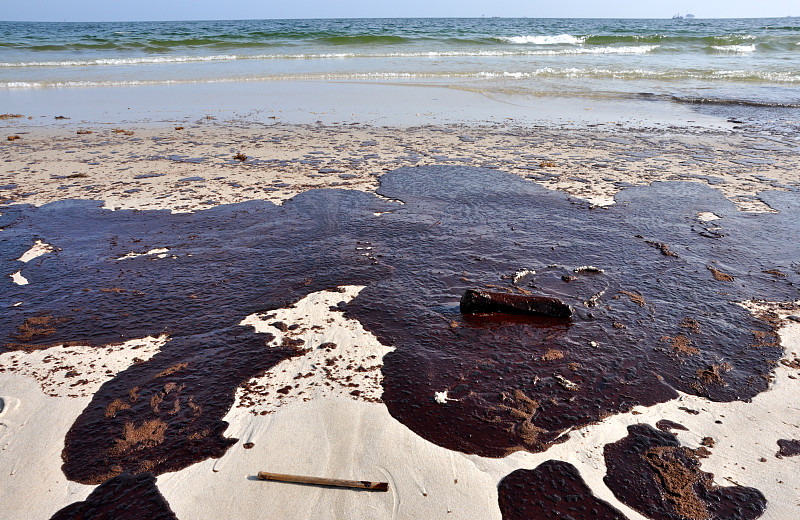 石油泄漏在靠近水的沙滩上图片下载