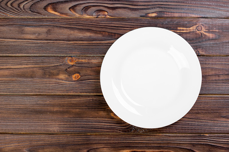 俯视图的空白色食物盘上的木材背景。图片下载